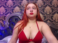A young, flirtatious, and very charismatic redhead with a spontaneous personality who enjoys talking and connecting with people. She has a curvaceous figure, a striking presence, and a feminine style that combines sweetness, confidence, and playfulness. She